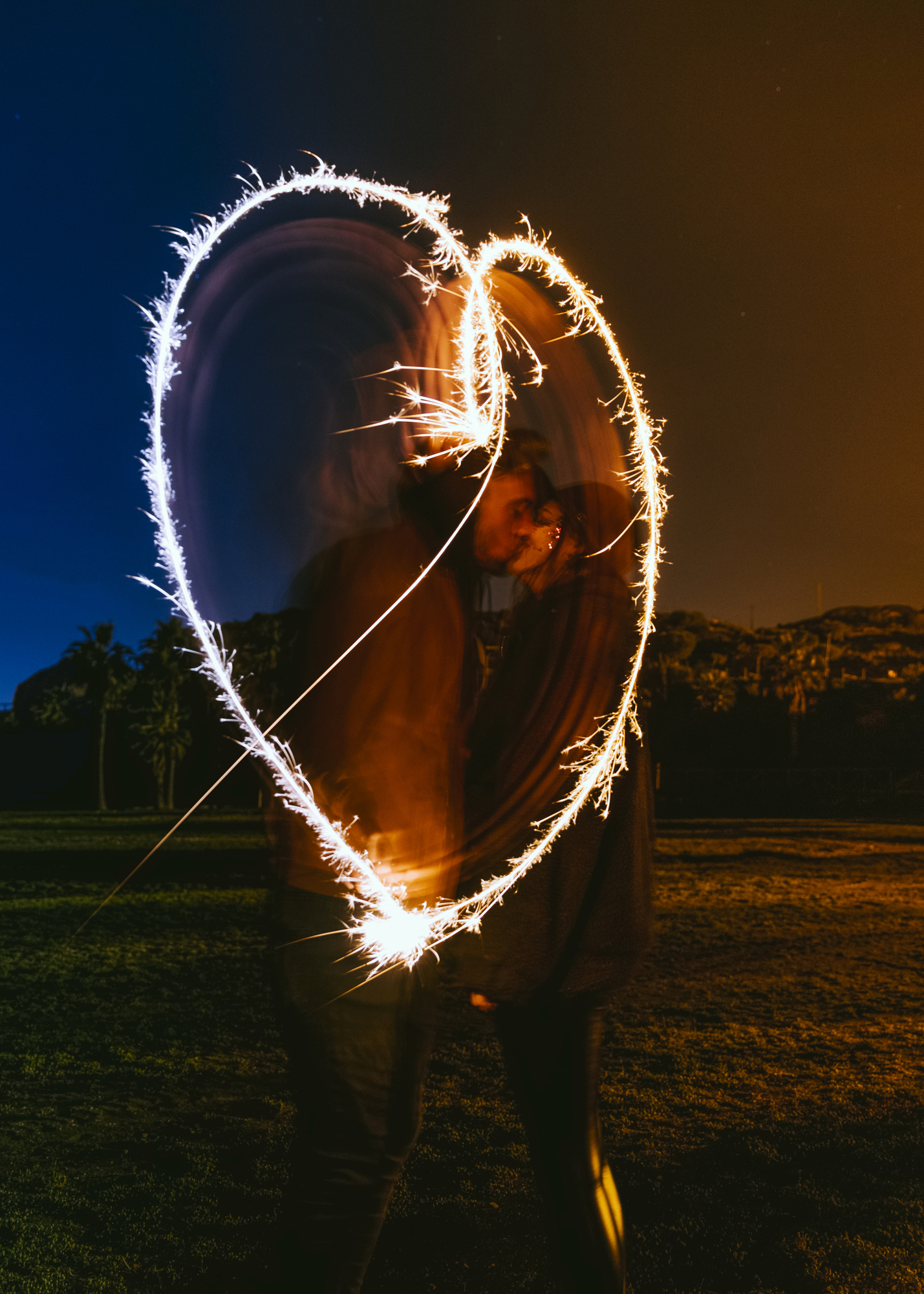 Couple-kissing-near-heart-drawing-from-sparklers-dark-street